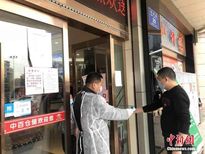图为3月24日,湖北孝感中百仓储,工作人员为顾客测量体温。中新社记者 梁婷 摄 探访湖北孝感:小城渐寻烟火气 返岗复工正当时